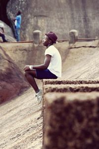 Side view of woman sitting against wall