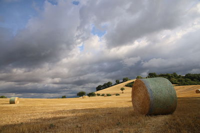 Hay bales on field against sky