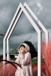 Portrait of young woman standing against sky