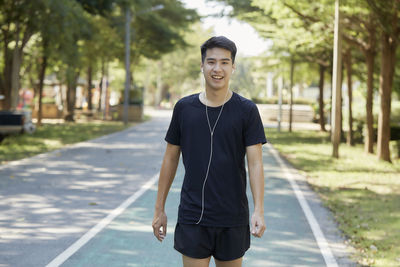 Portrait of young man standing on footpath