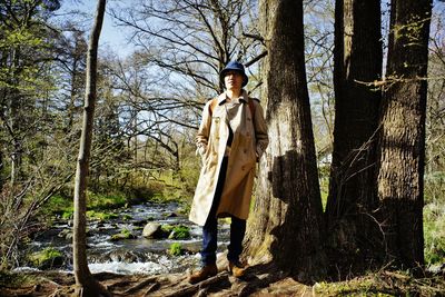 Portrait of young woman standing against trees in forest