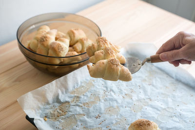 Close-up of hand holding croissant on table