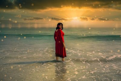 Woman standing on beach against sky during sunset