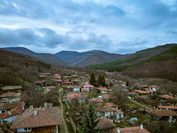 Aerial view of townscape by mountain against sky