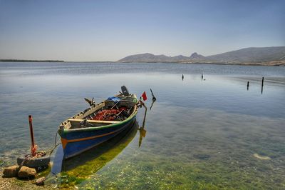 Boat moored on sea against clear sky