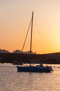 Sailboats in sea against clear sky during sunset