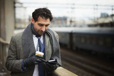 Businessman using phone at train station