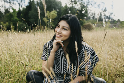 Smiling young woman sitting on field