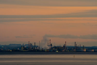 Illuminated factory against sky during sunset