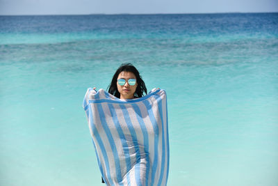 Portrait of young woman standing in sea against sky