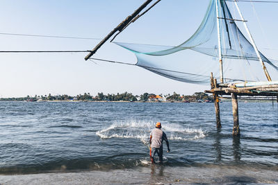 Rear view of man fishing in sea