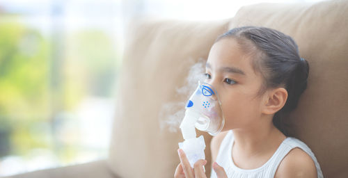 Girl using steam inhaler at home