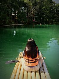 Rear view of woman sitting on pool raft in lake