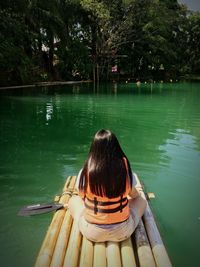 Rear view of girl sitting on boat in lake