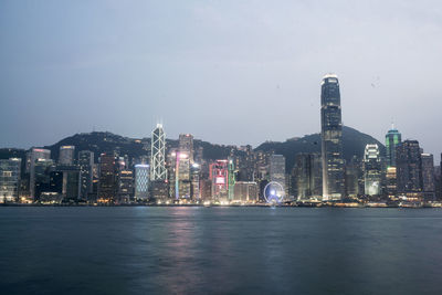 Illuminated cityscape against sky at dusk