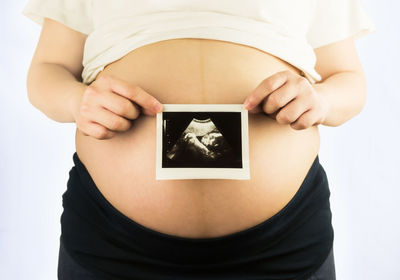 Midsection of woman holding umbrella against white background