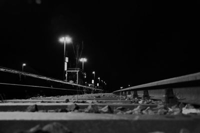 Illuminated railroad tracks against sky at night