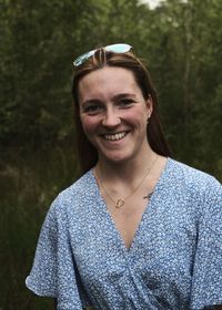 Portrait of young woman standing against trees