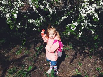 Full length of girl standing by flowering plants on field