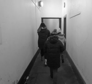 Rear view of mother and daughter walking on illuminated corridor