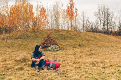 Backpacker sitting on field during autumn