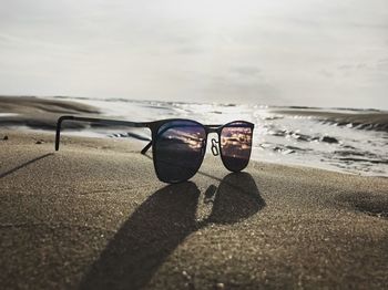 Close-up of sunglasses on beach against sky