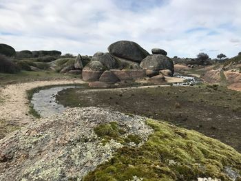 View of rocks on landscape against cloudy sky