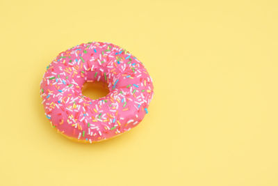 High angle view of multi colored candies against yellow background