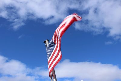 Low angle view of flag flying against sky