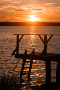 Silhouette pier over sea against sky during sunset