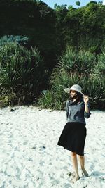 Full length of woman walking on sand against trees