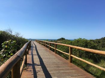 Wooden footbridge against clear blue sky
