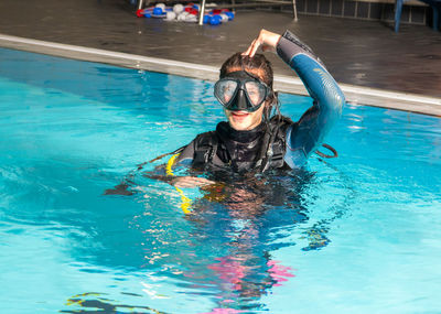 Young woman wearing swimming goggles in pool