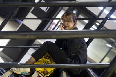 Portrait of businesswoman sitting on steps at railroad station