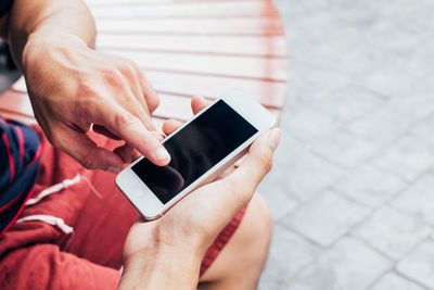 Person holding mobile phone for friend outdoors