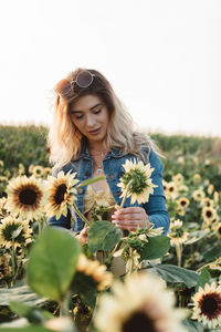 Beautiful young woman with flower petals on field