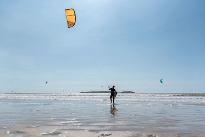 Man with umbrella on sea shore against sky