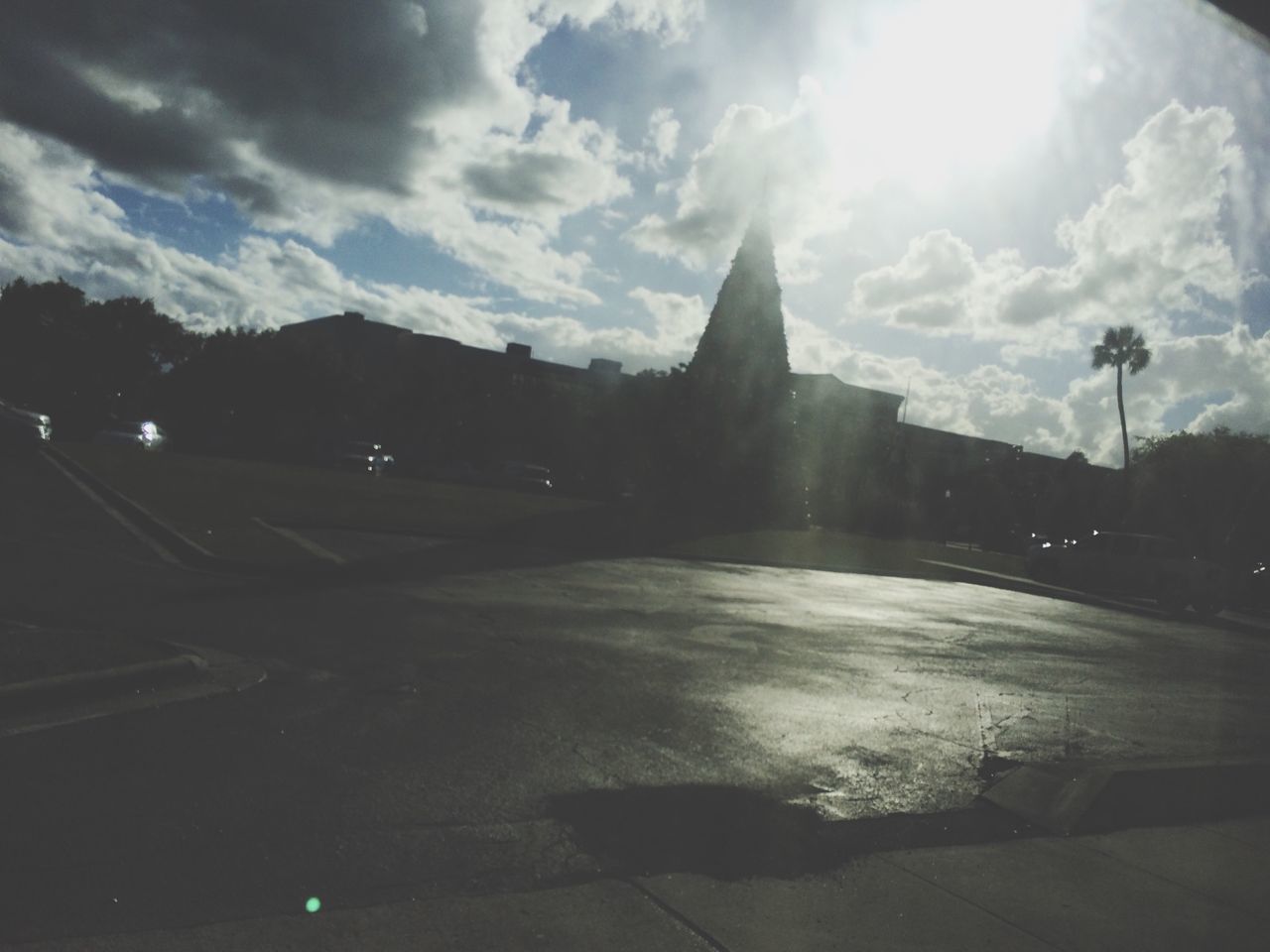 sky, building exterior, architecture, built structure, cloud - sky, transportation, street, road, car, sunbeam, city, sunlight, street light, sun, cloud, lens flare, cloudy, land vehicle, mode of transport, road marking