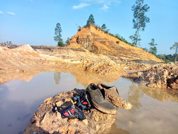 Rock formation by lake against sky