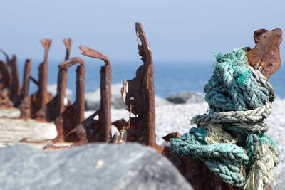 Close-up of rope tied on rusty metal against sea
