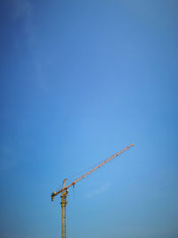 Low angle view of crane against blue sky