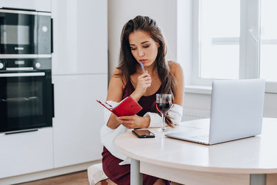 Young woman using phone while sitting on table