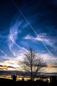 Low angle view of bare trees against cloudy sky