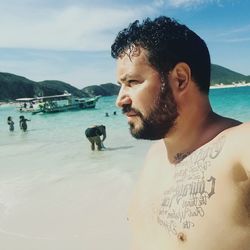 Profile view of shirtless man standing at beach