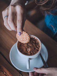 Midsection of woman holding coffee cup on table