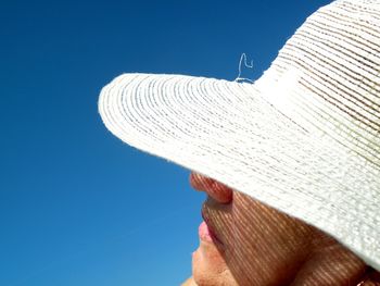 Cropped image of woman wearing sun hat against clear blue sky