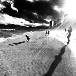 People in sea against cloudy sky