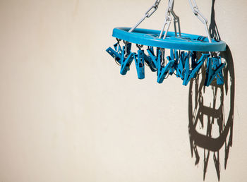 Low angle view of blue plastic clothespin against wall