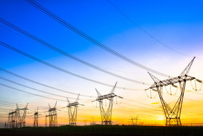 Low angle view of silhouette electricity pylon against sky during sunset