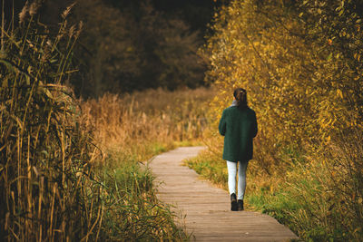 Rear view of woman walking on footpath